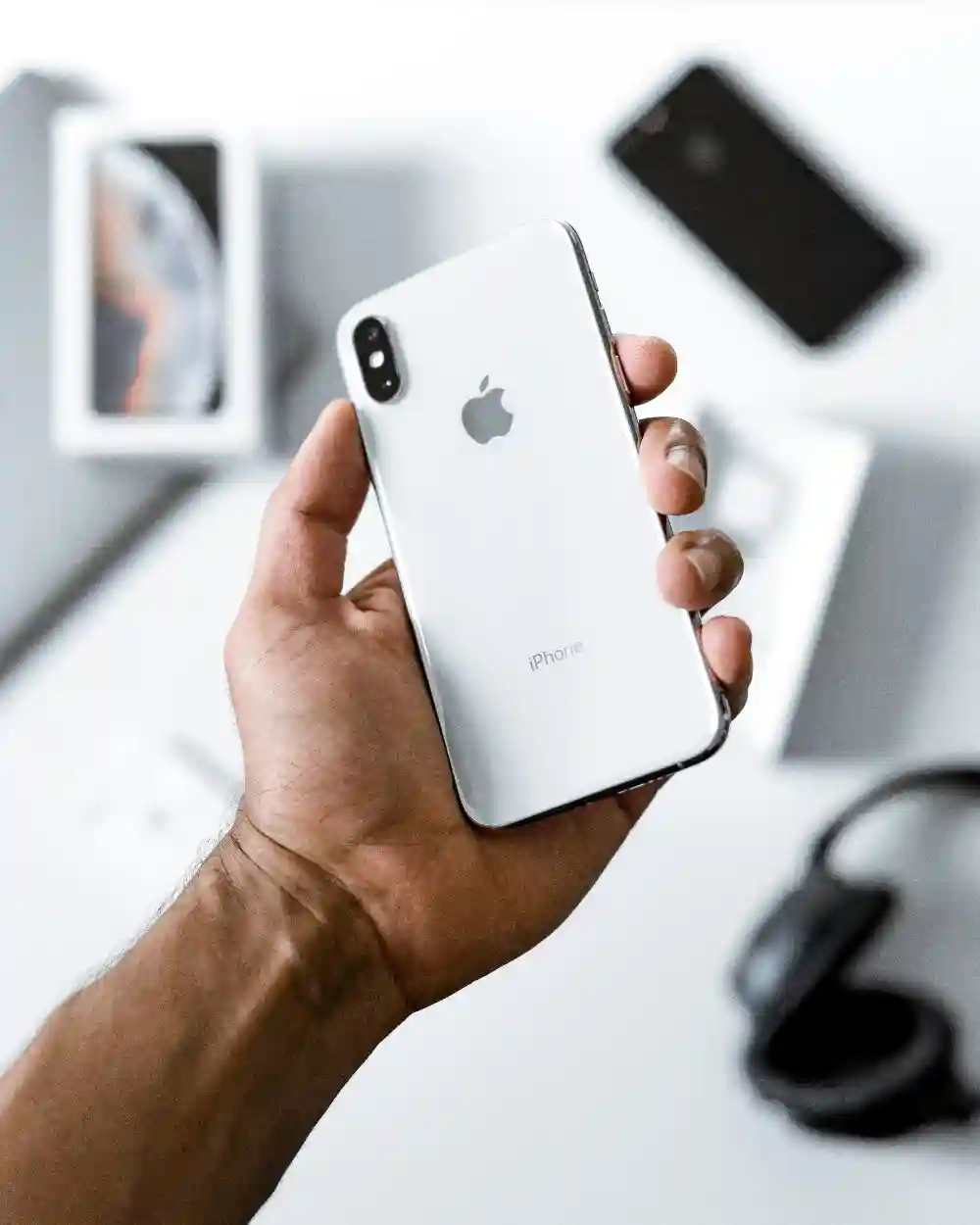 Smartphone held in hand with boxed phones behind